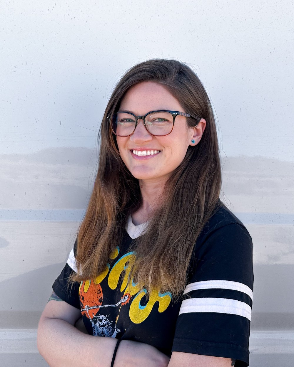 Tee, smiling with arms folded, leaning against the side of her van