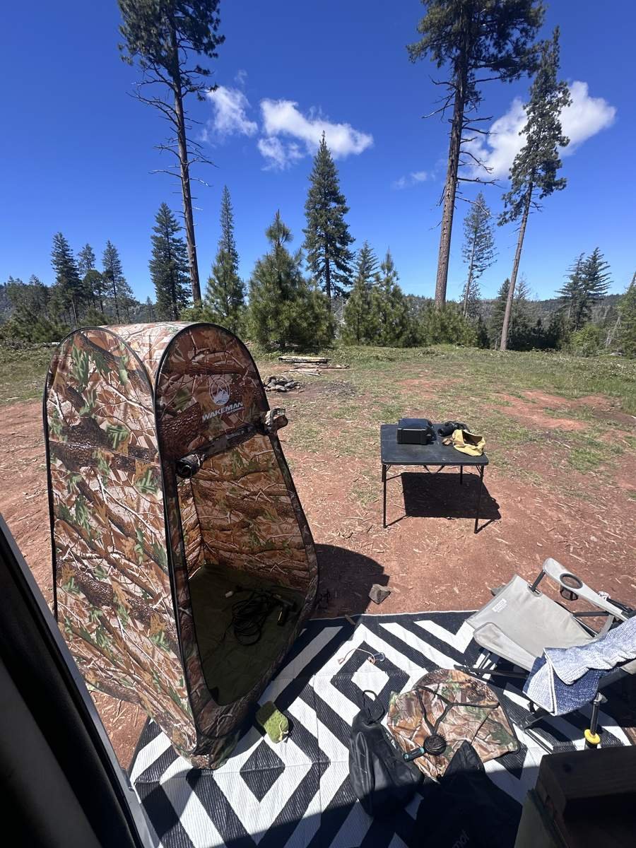 The full van life shower setup with shower tent and propane water heater at a dispersed campsite